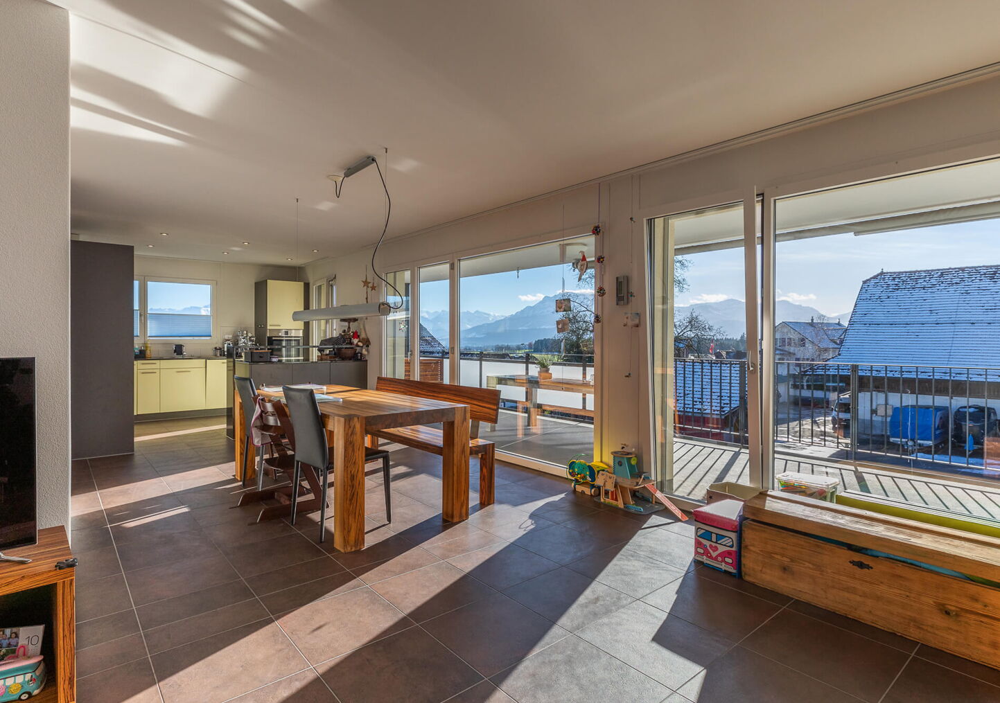 Immobilienfotografie: Grosses, helles Wohnzimmer mit Blick auf die Wohnküche und den grossen Balkon