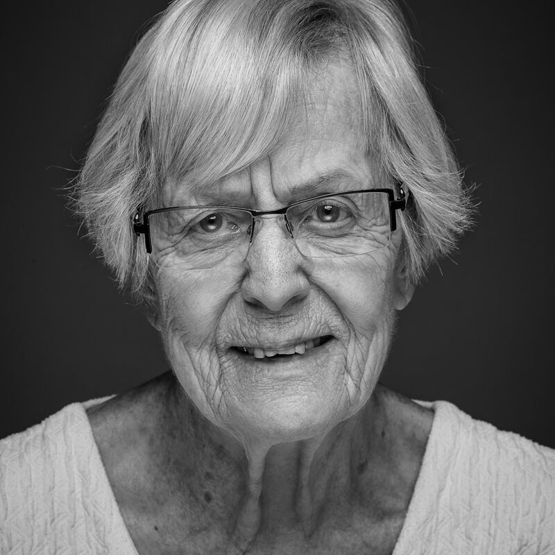 Portraitfotografie von älterer Frau mit grauen Haaren und Brille
